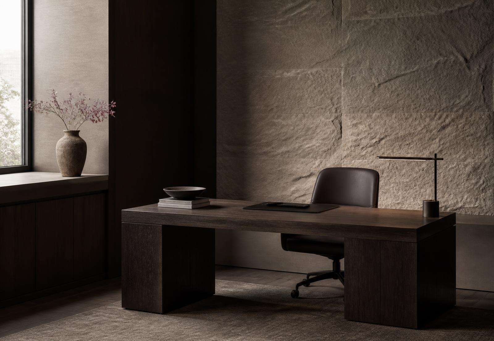 A quiet private office with a dark wood desk against a textured stone wall